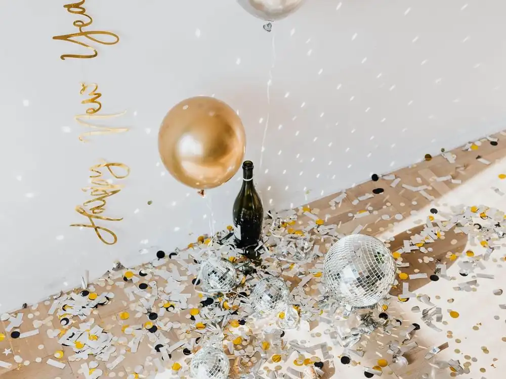 Celebration setup with champagne, balloons, confetti and disco balls for a party